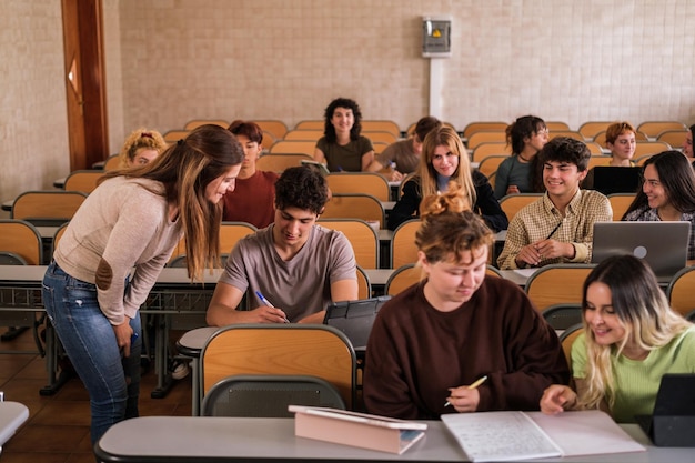 University professor attends to a student personally in the classroom with all her classmates