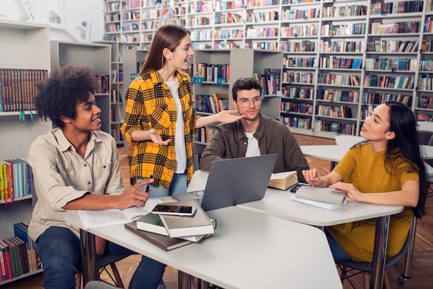 大学生は一緒に図書館で勉強しています。チームワークと準備の概念