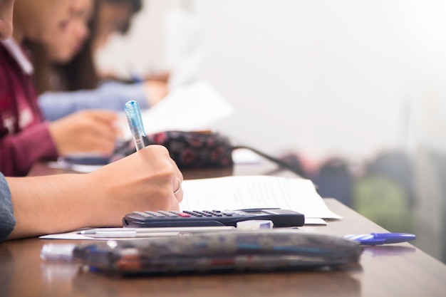 University students do quiz, test or studies from the teacher in a large lecture room. Students in uniform attending exam classroom educational school.