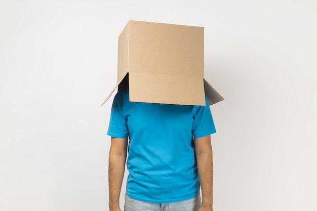 Unknown anonymous man wearing blue T shirt standing with cardboard box on his head having fun