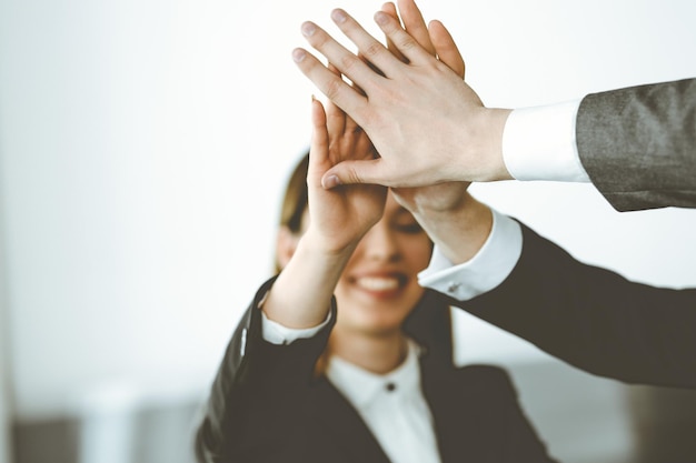 Unknown business people group joining hands in modern office Businessmen and women making circle with their hands as a team closeup