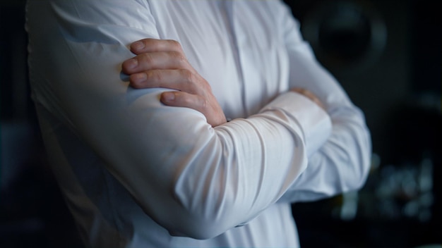 Unknown businessman standing dark restaurant interior Closeup folded man hands