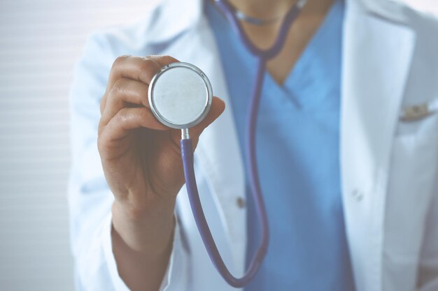 Unknown doctor woman holds stethoscope head, close-up. physician ready to examine and help patient. helping and insurance in health care, best treatment and medicine concept