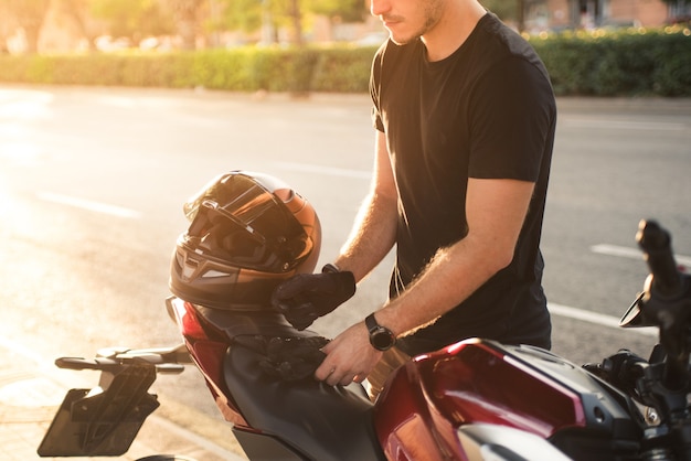 Unknown, faceless person of a young biker preparing for his motorcycle outing in the city.