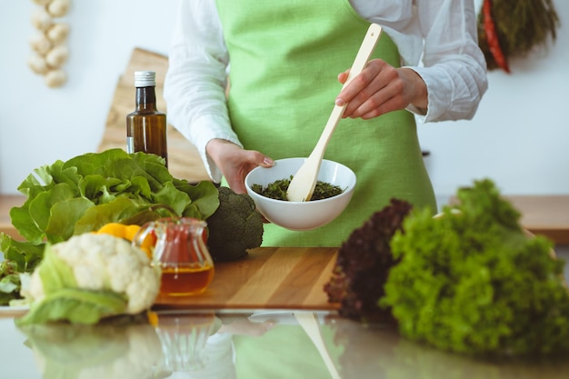 Неизвестные человеческие руки готовят на кухне. Женщина занята овощным салатом. Здоровое питание и концепция вегетарианской пищи.