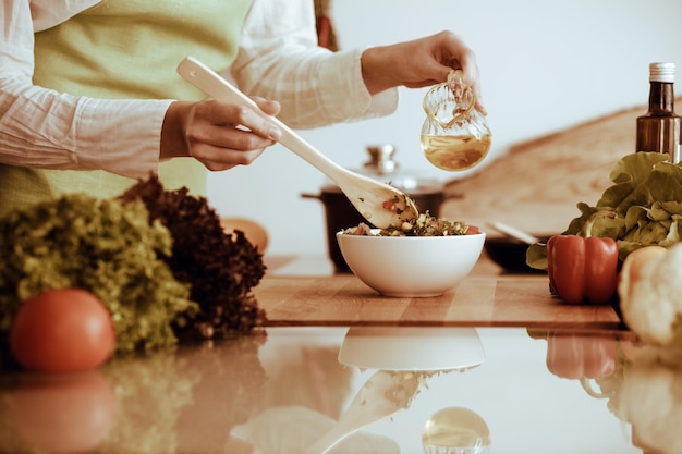 Unknown human hands cooking in kitchen. Woman is busy with vegetable salad. Healthy meal, and vegetarian food concept.