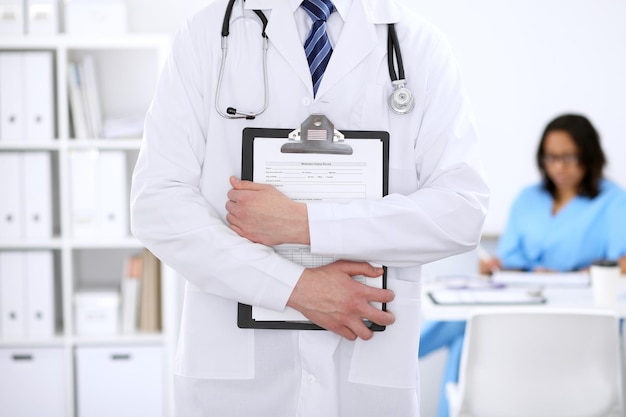 Unknown male doctor with stethoscope and clipboard, close up.