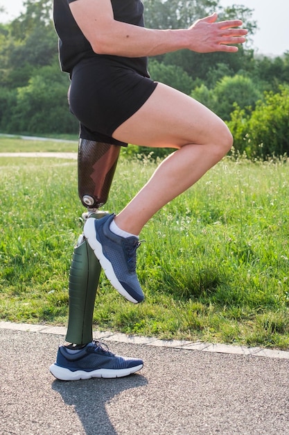 Unknown man with prosthetic leg exercising outdoors in the park