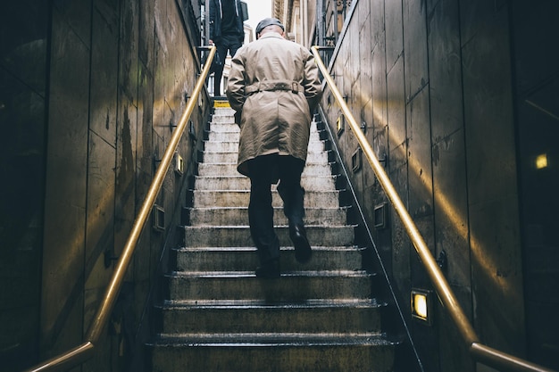 Unknown older man walking up the old stone stairs during\
rain