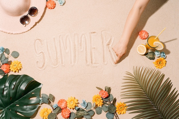 Unknown person writing the word summer with his finger on a sandy beach