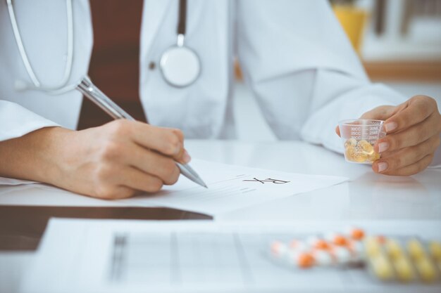 Photo unknown woman-doctor fills up prescription form. close-up. panacea and life save, prescribe treatment, legal drug store. medicine concept.