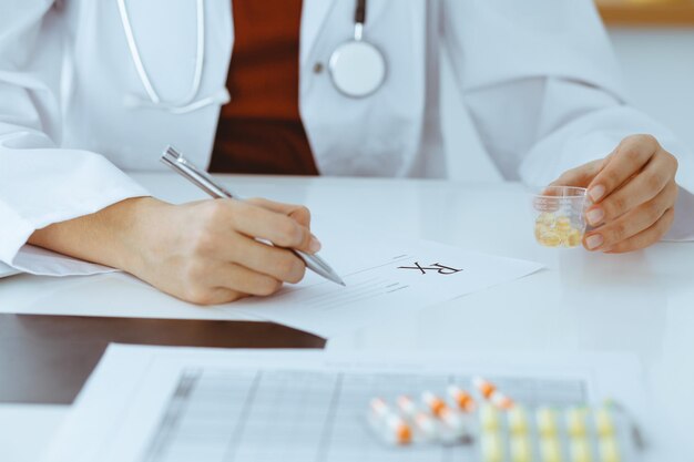 Unknown woman-doctor fills up prescription form. close-up. Panacea and life save, prescribe treatment, legal drug store. Medicine concept.