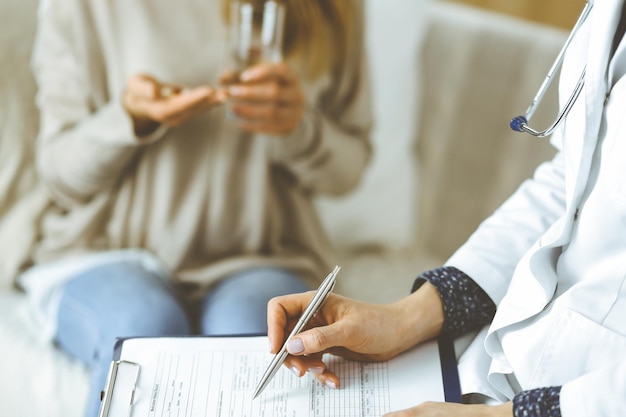 Photo unknown woman-doctor and patient discussing current health examination while sitting indoors. stay at home concept during coronavirus pandemic and self isolation quarantine.