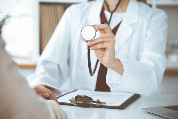 Unknown woman-doctor with a stethoscope in the hands. Physician is ready to examine a patient, close-up of hands. Medicine concept.