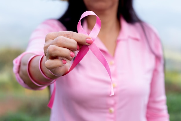 An unknown woman holds a pink breast in front of the camera symbolizing Women's Day