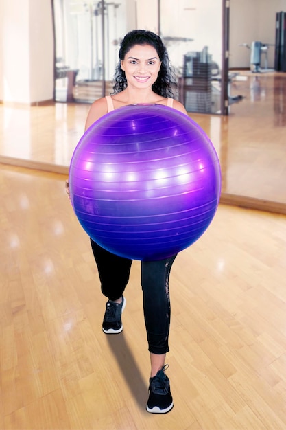 Unknown woman holds yoga ball in fitness center