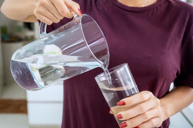 Foto donna sconosciuta che versa acqua nel bicchiere.