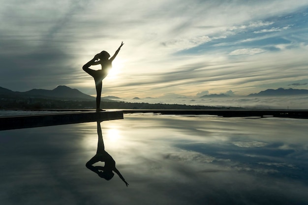 Unknown woman practicing yoga at the poolside