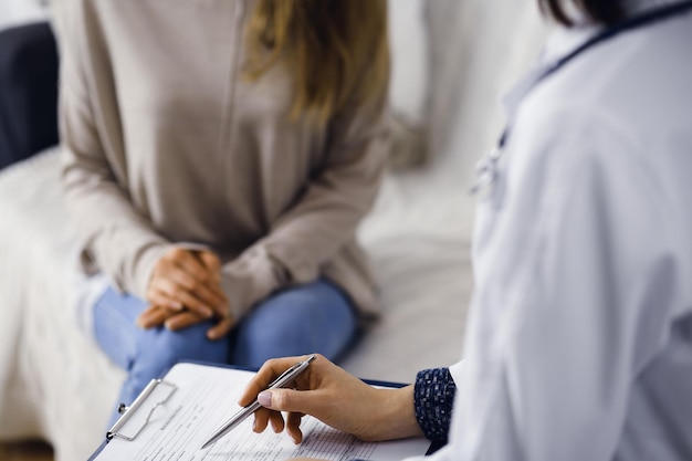 Unknown womandoctor and patient discussing current health examination while sitting indoors Stay at home concept during Coronavirus pandemic and self isolation quarantine