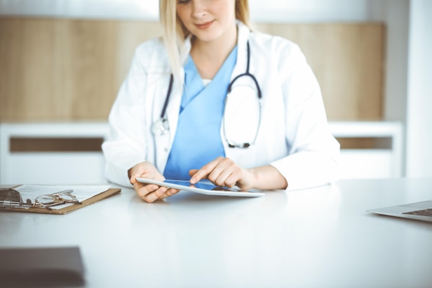 Unknown womandoctor standing in clinic and using tablet pc closeup Data and best service in medicine and healthcare