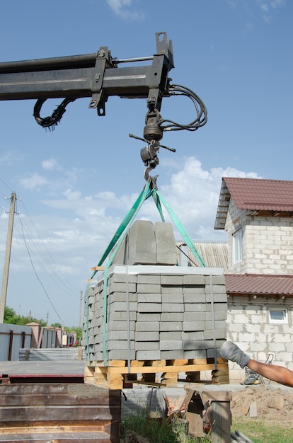 Unloading paving slabs from a truck a manipulator workers unload build