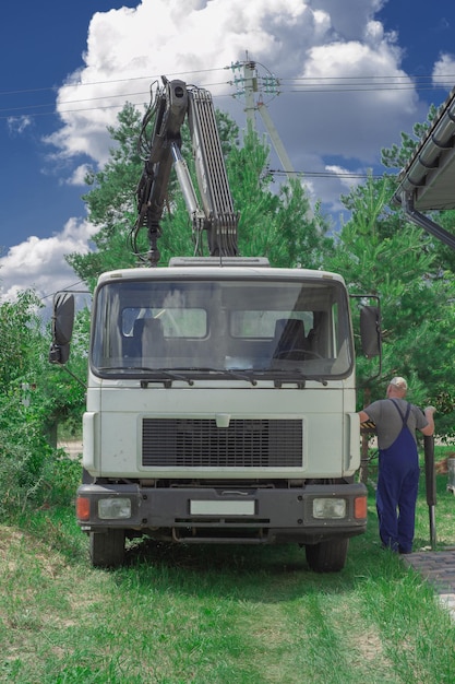 Scarico delle lastre di pavimentazione da un camion gli uomini scaricano le lastre di pavimentazione utilizzando un manipolatore gli operai scaricano i materiali da costruzione da una grande macchina