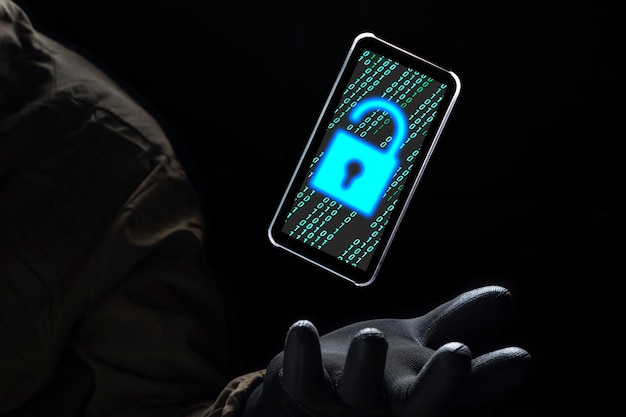 Photo unlock icon with green binary code on smartphone floating above of hacker hand in dark background