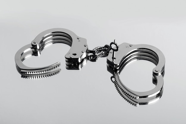 Unlocked pair of steel handcuffs or manacles on white in a concept of justice and law enforcement or sex fetish and bondage