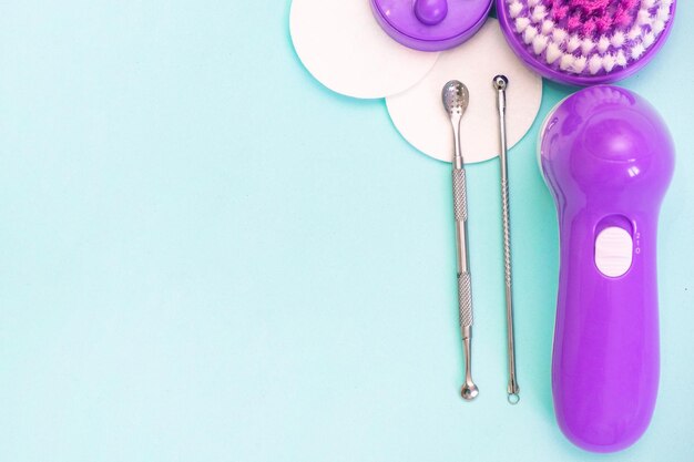 Uno scoop and facial massager are on a soft turquoise background. flat lay, cosmetology and tools concept