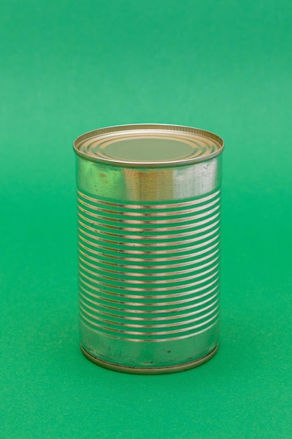 Photo unopened tin can with blank edge on green background