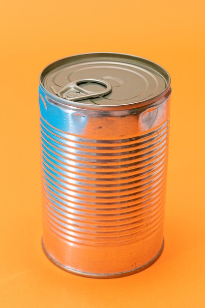 オレンジ色の背景に空白のエッジを持つ未開封のブリキ缶