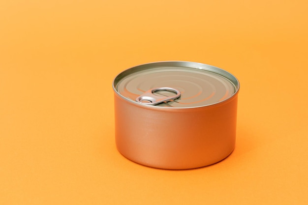 Photo unopened tin can with blank edge on orange background