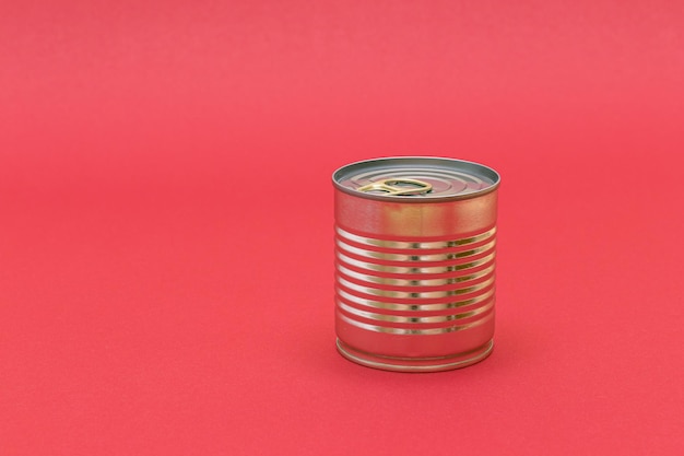 Photo unopened tin can with blank edge on red background