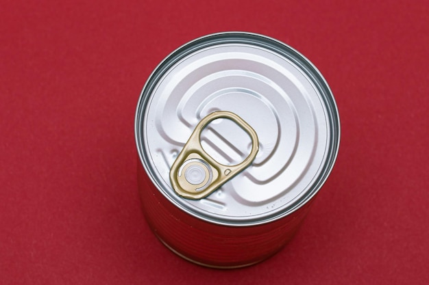 Unopened tin can with blank edge on red background