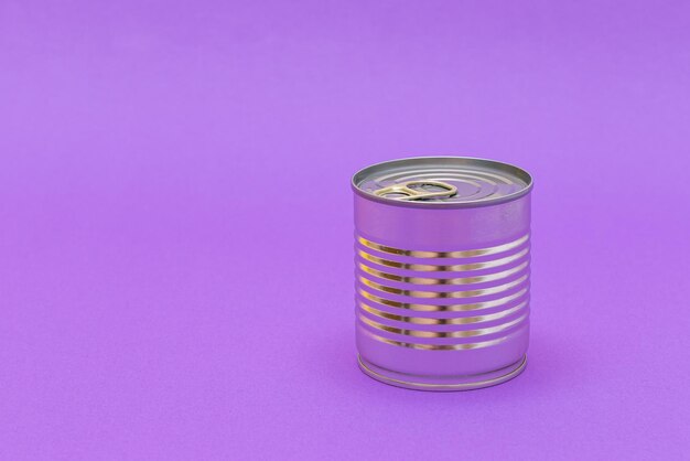 紫色の背景に空白のエッジを持つ未開封のブリキ缶