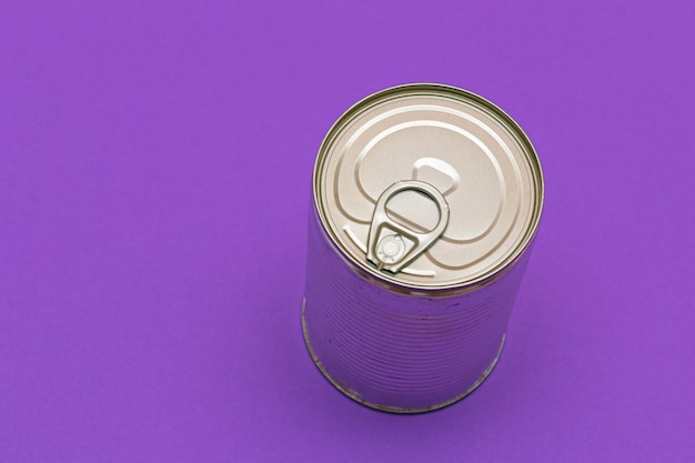 Photo unopened tin can with blank edge on violet background