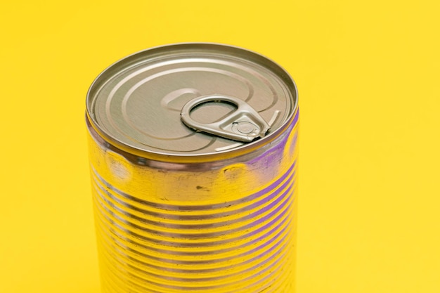 Unopened tin can with blank edge on yellow background
