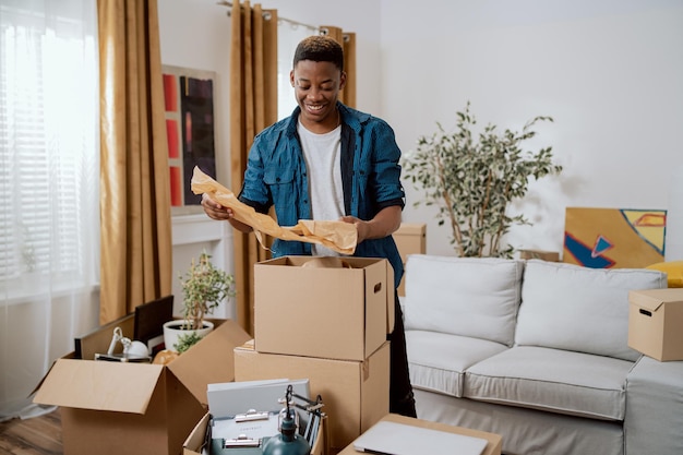 Unpacking cardboard boxes after moving man cleans new apartment cluttered with things from previous