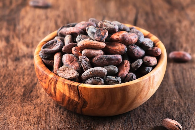 Unpeeled cocoa bean on wooden rustic background closeup Copy space