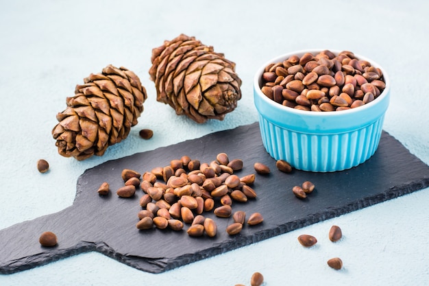 Unpeeled pine nuts and cones on a slate board and in a bowl. Gifts of Siberia. Detox and cure for insomnia. Healthy vitamin nutrition