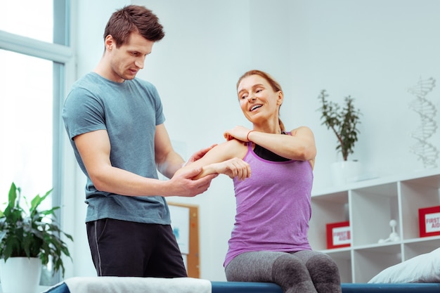 Unpleasant pain. Nice positive woman pointing at her back while feeling an unpleasant pain there