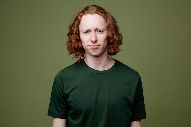 Unpleased looking at camera young handsome guy wearing green t shirt isolated on green background