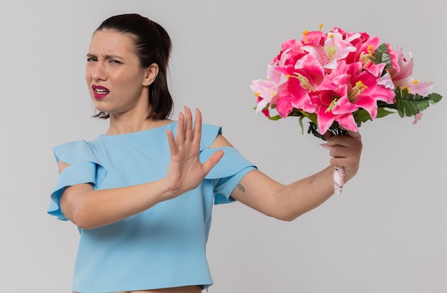 Unpleased pretty young woman holding bouquet of flowers 