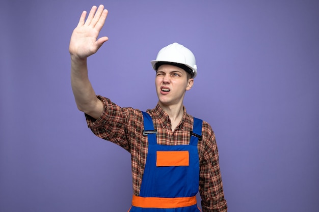 Unpleased showing stop gesture young male builder wearing uniform 