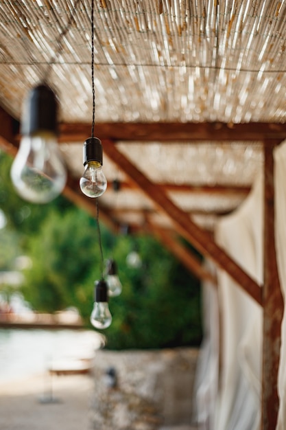 Unpluged garland of incandescent bulbs under the thatched ceiling