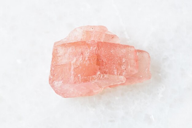 Unpolished Rhodochrosite crystal on white marble