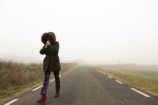 Photo unrecognisable woman walking on a cold and foggy mountain road