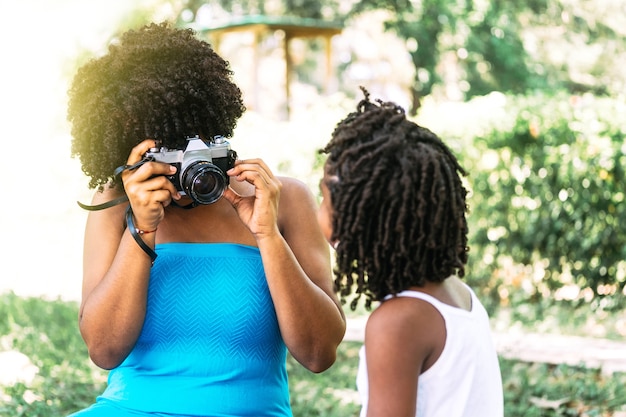 Unrecognizable Adult woman holding an analog camera making a selfie to a little boy