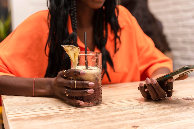 휴대 전화를 사용하는 동안 음료를 들고 인식할 수 없는 아프리카계 미국인 여자