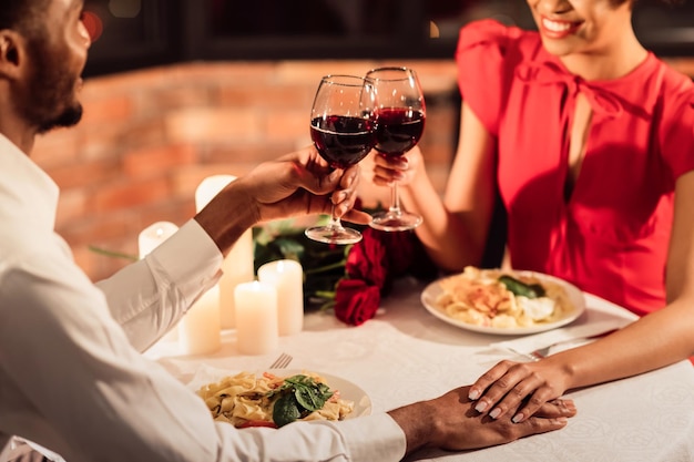 Unrecognizable Afro Lovers Clinking Glasses Holding Hands In Restaurant Cropped